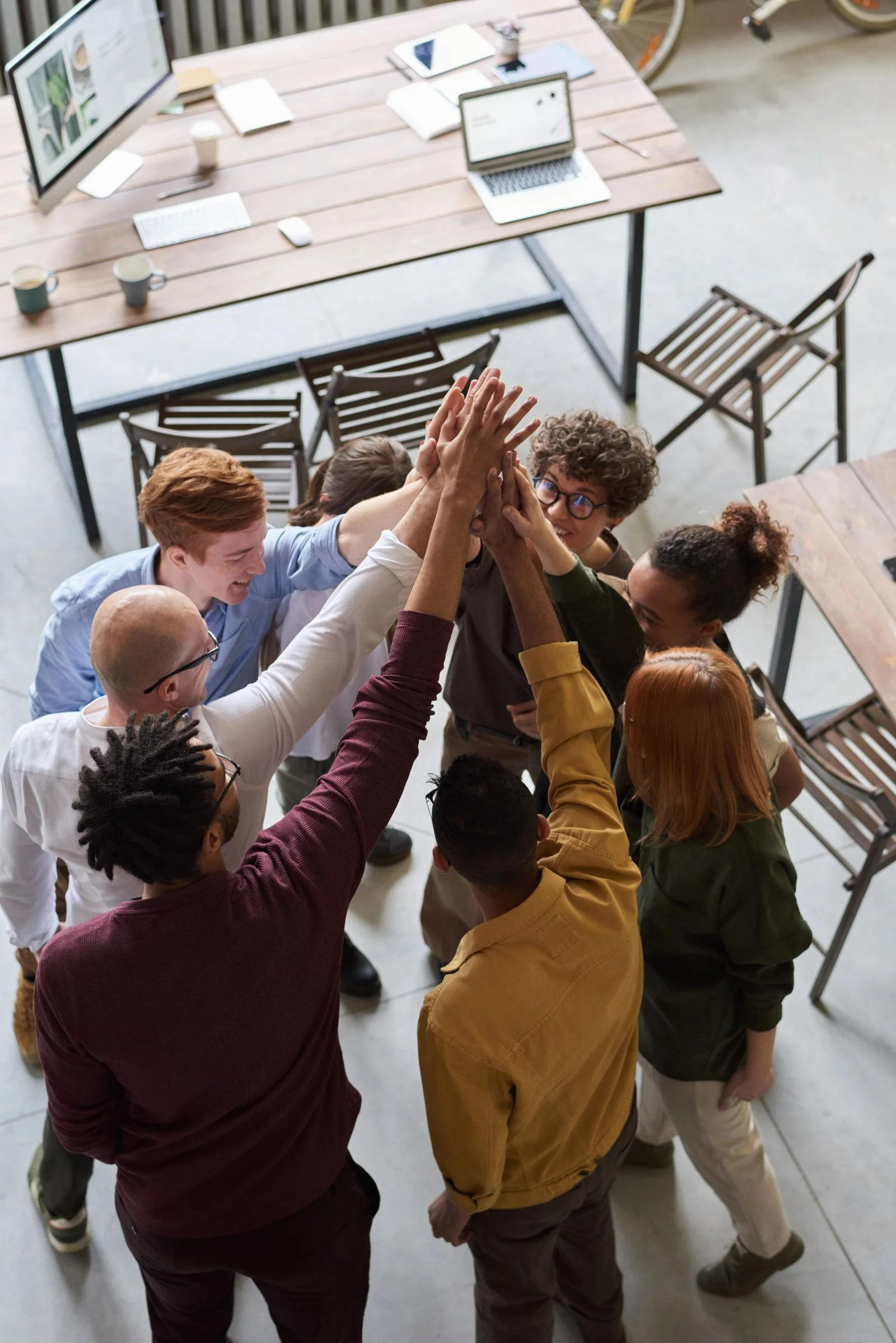 A group raising their joined hands around a table